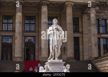 Statua di Schiller con pergamena e sala concerti sullo sfondo Foto Stock