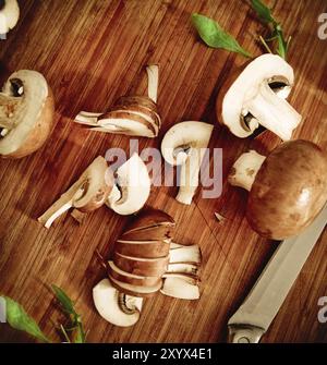 Preparazione di pasto processo. Coltello, insalata di funghi, sullo sfondo di legno Foto Stock