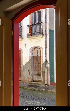 La vecchia porta in architettura coloniale si è deteriorata dal tempo visto attraverso un altra porta anche le vecchie e con la stessa architettura della città di Ouro Preto Foto Stock