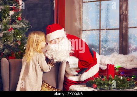 Babbo Natale e la bambina. Scena di natale. Ragazza raccontando il suo augurio natalizio a Santa Claus in prossimità della struttura ad albero di Natale Foto Stock