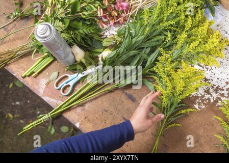 Tavolo da lavoro fiorista. Fiorista al lavoro che crea un bouquet in un negozio di fiori. vista dall'alto Foto Stock