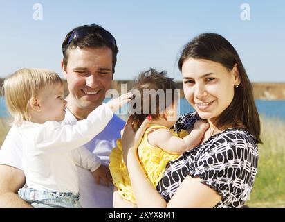 Famiglia giovane felice con due bambini vicino al lago all'aperto Foto Stock