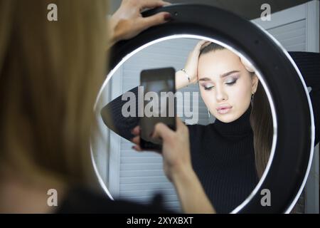 Make up Artist tenendo mobile photo per il modello con il trucco Foto Stock