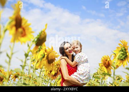 Felice sua madre e la sua piccola figlia nel campo di girasoli Foto Stock