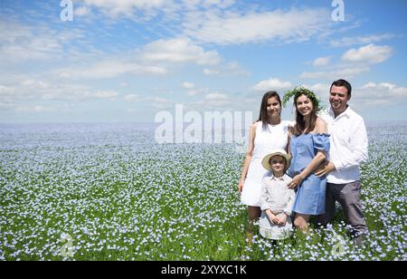 Ritratto di una giovane famiglia incinta nel campo di lino. Orario estivo Foto Stock