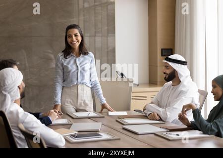 Felice imprenditrice ispanica che tiene un incontro con diversi colleghi Foto Stock