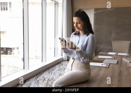 Donna d'affari di successo che utilizza il telefono cellulare nella sala riunioni Foto Stock