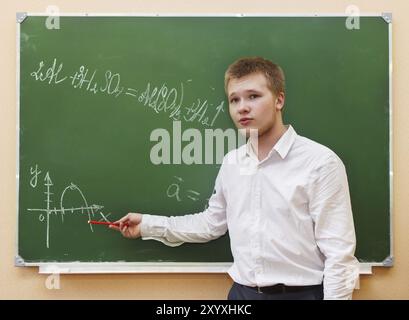 Studente ragazzo in piedi vicino alla lavagna in aula Foto Stock