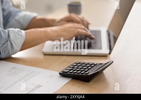 Primo piano della calcolatrice e delle mani sul laptop Foto Stock
