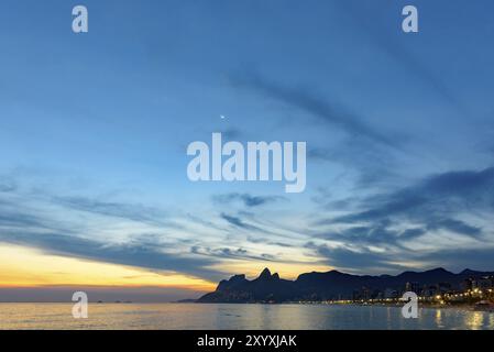 Paesaggio delle spiagge di Arpoador, Ipanema e Leblon a Rio de Janeiro durante il tramonto con le sue luci, la luna e il cielo e la collina due fratelli e GA Foto Stock