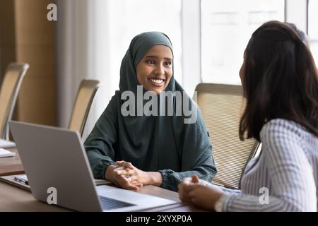 Felice giovane donna araba professionale di affari che parla con un collega Foto Stock