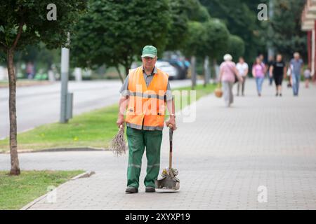 Un pulitore maschile con una scopa e una padella pulisce le strade. Foto Stock