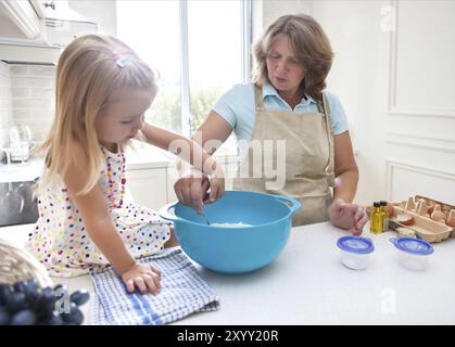 Carino bambina la cottura con sua nonna a casa Foto Stock