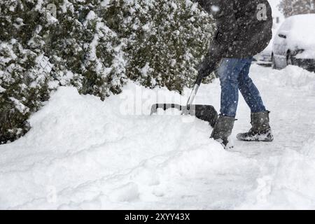 Donna che pulisce la neve sul marciapiede Foto Stock