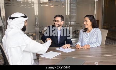 Allegra coppia sposata europea che stringe la mano a un consulente d'affari arabo Foto Stock