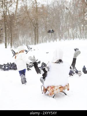 Bambina divertendosi su di una slitta nella neve con la madre. Giornata invernale Foto Stock