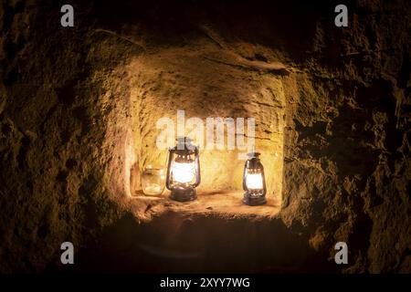 Una lampada a paraffina brucia di notte su un piedistallo in un vecchio castello in rovina su arenarie Foto Stock