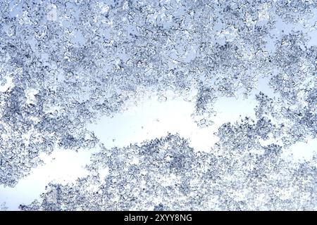 Sfondo invernale, consistenza di gocce di ghiaccio, pioggia ghiacciata e neve sul vetro, vista dalla finestra nel cielo invernale Foto Stock