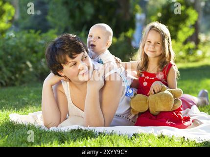 La madre e i suoi bambini all'aperto. Felice la mamma e i suoi bambini giocare nel parco insieme. Outdoor ritratto di famiglia felice Foto Stock