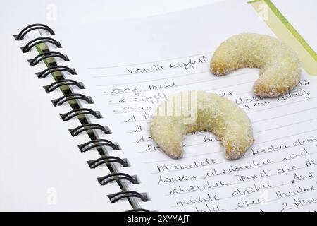 Biscotti di Natale, mezzalune di vaniglia, su un ricettario Foto Stock