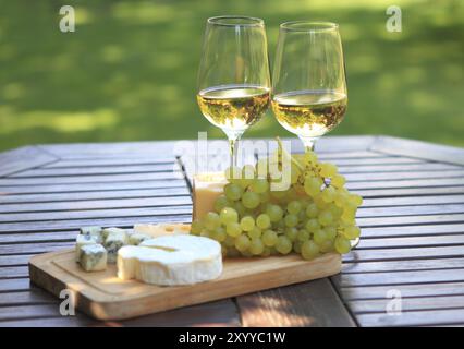 Vari tipi di formaggio, uva e due bicchieri di vino bianco Foto Stock