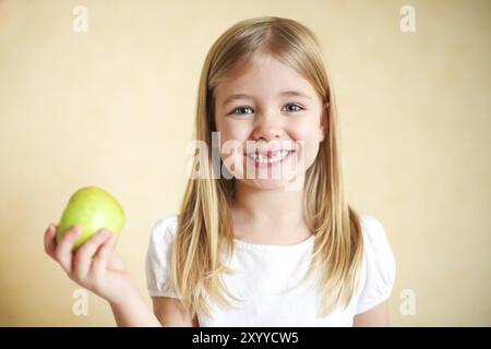 Portreit poco divertente ragazza bionda con mela verde Foto Stock