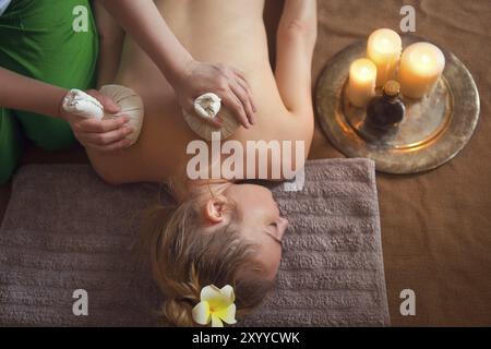 Donna getting tailandese alle erbe comprimere massaggio nella spa. Close up Foto Stock