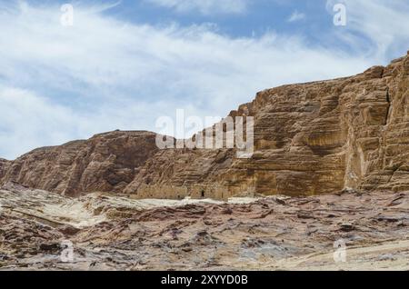 Rovine di case nel deserto sullo sfondo di alte montagne rocciose e cielo blu con nuvole bianche in Egitto Dahab Sud Foto Stock