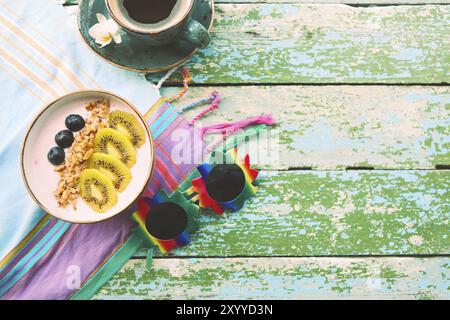 Tazza di muesli con yogurt e frutta su sfondo turchese Foto Stock