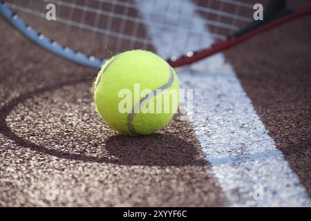 Ombre di racquet che circondano una palla da tennis vicino alla linea bianca sul campo all'aperto in sole, sport e concetto di stile di vita attivo Foto Stock