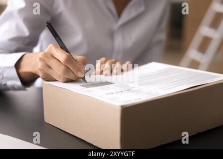 Primo piano ritagliato che ha sparato a una donna d'affari sconosciuta etichettando o firmando una scatola di imballaggio Foto Stock