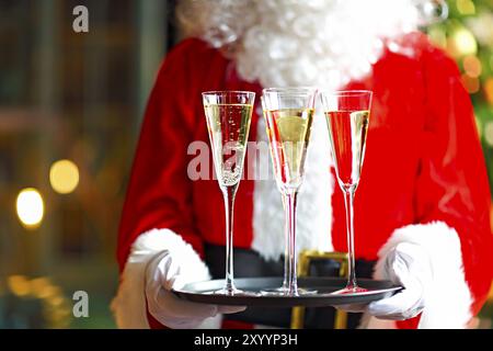 Santa Claus holding champagne bicchieri sul vassoio. Primo piano Foto Stock