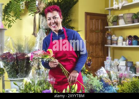 Fiorista donna felice, che fa accordi e sorride alla telecamera. Proprietario di un negozio di fiori per piccole imprese Foto Stock