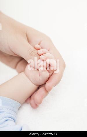 Madre amorevole che tiene la mano del bambino appena nato con le dita piccole Foto Stock