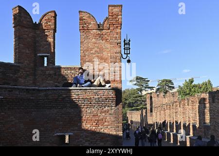 I giovani fanno una siesta e guardano i passanti sul ponte Foto Stock