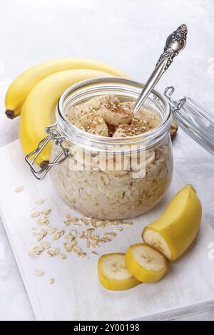 Sana colazione con vecchio stile di avena, miele e banana in un vaso su bianco tavolo in legno Foto Stock