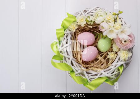 Cesto di uova di pasqua con fiori di colore bianco su sfondo di legno Foto Stock