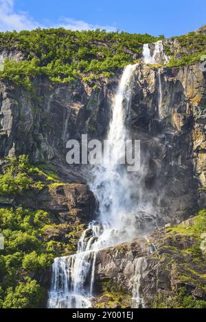 Cascata, scogliera di montagna e alberi verdi sulla strada per Briksdal o il ghiacciaio Briksdalsbreen a Olden, Norvegia, Europa Foto Stock