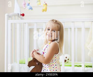 Poco carino ragazza nella nursery room con i giocattoli e cavallo di legno Foto Stock