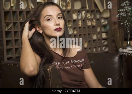 Una giovane donna siede su una poltrona sullo sfondo di interni vintage Foto Stock