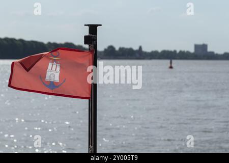 Primo piano di una bandiera con lo stemma della città di Amburgo e ancora sulla prua di un traghetto di HADAG Verkehrsbetriebe nel porto di Amburgo, Foto Stock