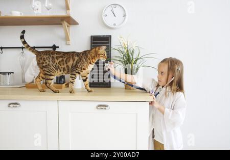 Bambina giocando con il veterinario il suo gattino sulla cucina. La cura degli animali concept Foto Stock