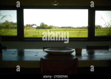 Angolo cucina con vassoio in argilla, sgabello da bar e finestra panoramica con vista sui campi di riso nella campagna Foto Stock