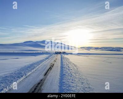 Vista aerea con drone. Strada ghiacciata in inverno in Islanda. Strade piene di neve durante l'inverno con cielo azzurro Foto Stock