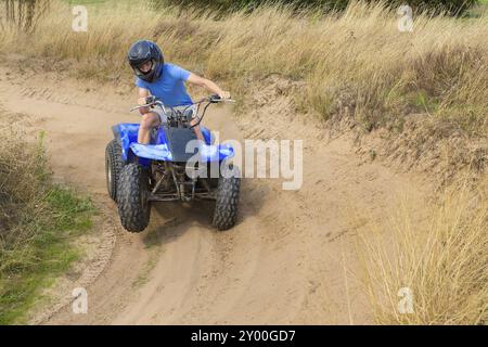 Giovane uomo europeo la guida quad attraverso la curvatura Foto Stock