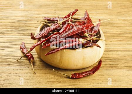 Peperoncino rosso essiccato in una ciotola di legno su un tavolo di legno Foto Stock