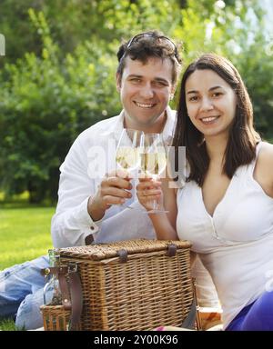 Giovane coppia felice che si gusta un bicchiere di vino bianco in giardino Foto Stock