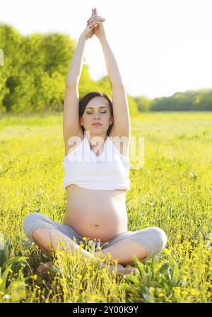 Un sano donna incinta fare yoga nella natura all'esterno. Tempo di primavera Foto Stock