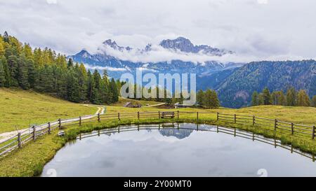 Prato alpino e Wuhnleger Weiher, sullo sfondo le cime del roseto, avvolte dalla nebbia, colpo di droni, Dolomiti, Provincia Autonoma di Bol Foto Stock