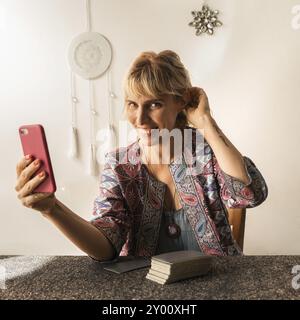 Lettore di tarocchi sorridente che tiene il telefono in mano mentre guarda la fotocamera Foto Stock